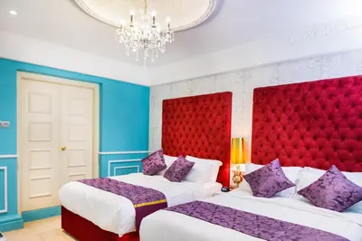 two beds in a room with blue and red at Apple Heritage Hotel in George Town