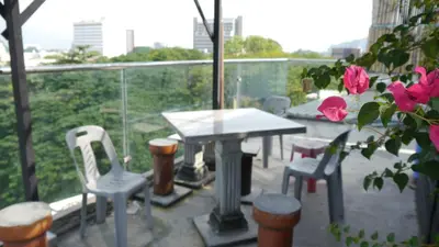 a table and chairs on a balcony with a table and roses at Abby by the river in Ipoh