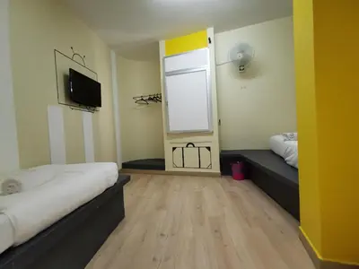 a room with two beds and a tv and a window at Abby by the river in Ipoh