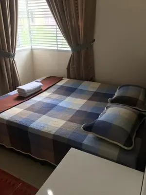 a bed in a room with a plaid blanket at Miker Homestay in Seri Iskandar