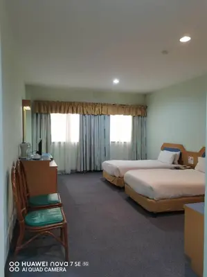 a hotel room with two beds and a chair at Coral Bay Resort in Pangkor