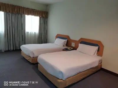 a hotel room with two beds and a window at Coral Bay Resort in Pangkor