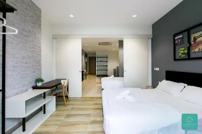 a bedroom with a white bed and a desk and a table at JOMSTAY Octagon Ipoh Suites in Ipoh