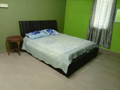 a bedroom with a bed and a table and green walls at Panorama Homestay in Jeram