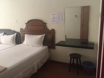 a bedroom with a bed and a mirror and a stool at Hotel Sri Malim Sungkai in Sungkai