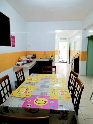 a dining room with a table and chairs and a kitchen at Sakura Guest House in Cameron Highlands