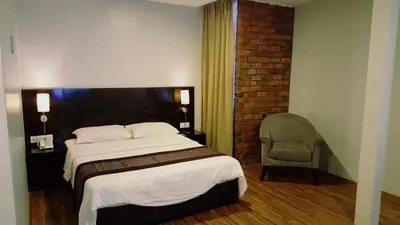 a bedroom with a large bed and a chair at Super 8 Hotel @ Georgetown in George Town