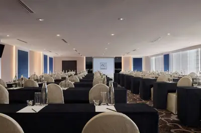 a conference room with tables and chairs and a screen at AC Hotel by Marriott Ipoh in Ipoh