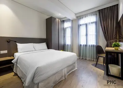 a bedroom with a large white bed and a desk at Macallum Central Hotel Managed by The Ascott Limited in George Town