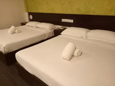 two beds in a hotel room with towels on them at Hotel Sri Bernam in Sabak Bernam