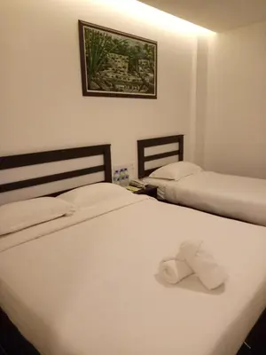 two beds in a hotel room with a towel laying on them at Hotel Sri Bernam in Sabak Bernam