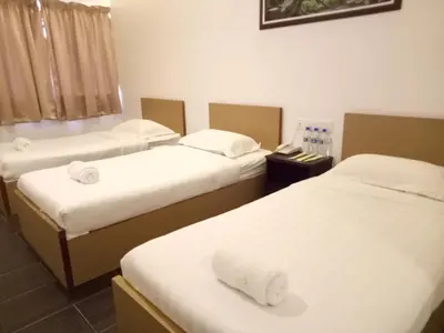 a room with three beds with white sheets and towels at Hotel Sri Bernam in Sabak Bernam