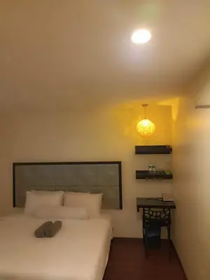 a bedroom with a white bed and a desk at M Season Boutique Hotel Sdn Bhd in Sungai Petani