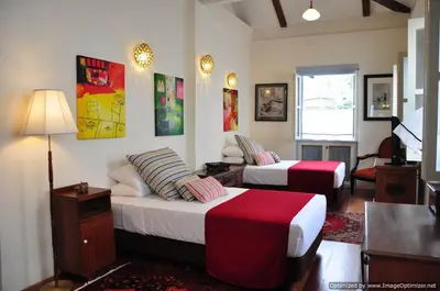 a bedroom with two beds and a table and a lamp at 23 Love Lane Hotel in George Town