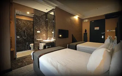 a hotel room with two beds and a shower at 1969 Business Suites Bandar Botani, Ipoh in Ipoh