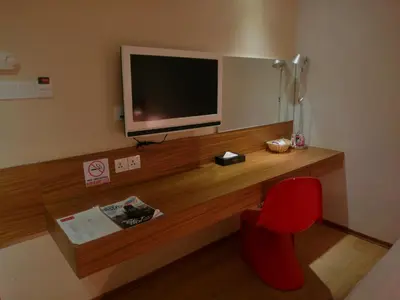 a room with a desk with a television and a red chair at French Hotel in Ipoh