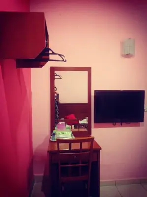 a room with a mirror and a desk with a television at Weng Kong Homestay in Slim River