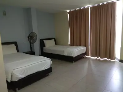 a bedroom with two beds and a window with curtains at Starview Hotel in Lumut