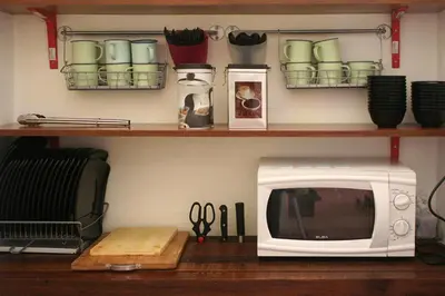 a microwave sitting on a wooden table next to a shelf at Red Inn Court in George Town