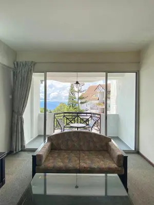 a couch in a living room with a large window at Habitat Fraser's Hill in Bukit Fraser