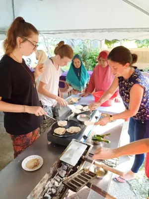 a group of people preparing food in a tent at Homestay Damai Sri Kota in Kepala Batas