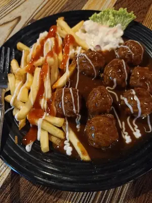 a black plate of food with meatballs and french fries at Homestay Damai Sri Kota in Kepala Batas