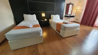 a hotel room with two beds and a chair at The Jerai Hotel Sungai Petani in Sungai Petani