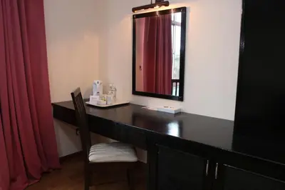 a desk with a mirror and a chair in a room at The Jerai Hotel Sungai Petani in Sungai Petani