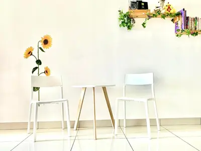 two white chairs and a table with flowers on a wall at HomeSweetHome in Perai