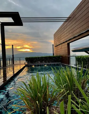 a swimming pool in front of a building with the sunset at HomeSweetHome in Perai