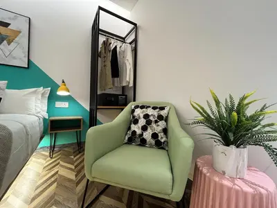 a bedroom with a green chair and a potted plant at Apple 1 Hotel Queensbay in Bayan Lepas