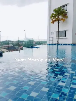 a swimming pool with a palm tree in front of a building at Taiping Centre Point Suite 7 by BWC in Taiping