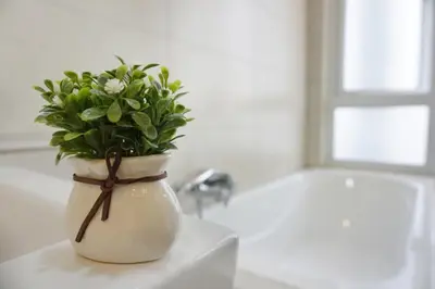 a white vase with a plant in it on a sink at PM Octagon Ipoh Duplex Suite (4-12paxs) in Ipoh
