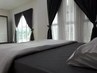 a bedroom with a large bed with windows at Greenville Homestay in Balik Pulau