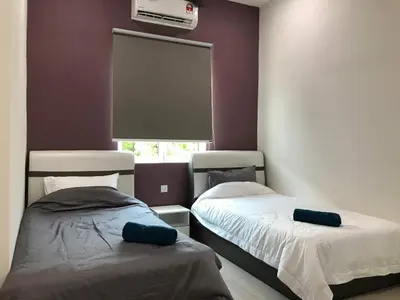 a bedroom with two beds and a window with a fan at Greenville Homestay in Balik Pulau