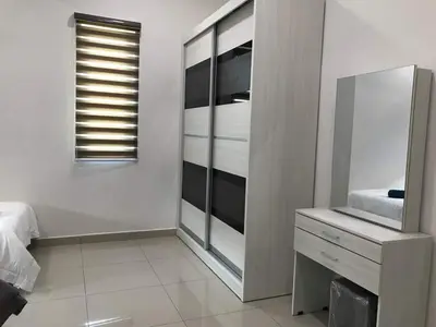 a white bedroom with a dresser and a mirror at Greenville Homestay in Balik Pulau