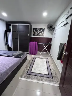 a bedroom with a bed and a closet with purple towels at Nadrah Cottage in Bayan Lepas