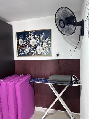 a room with a table and a fan on a wall at Nadrah Cottage in Bayan Lepas