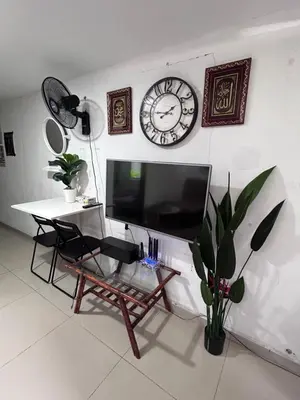 a living room with a tv and a table and a clock at Nadrah Cottage in Bayan Lepas