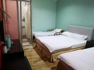 three beds in a room with green walls at Home Inn Hotel in Ipoh