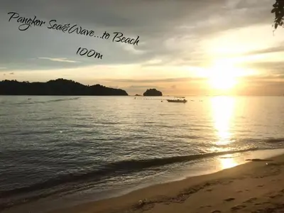 a sunset on the beach with a boat in the water at Sea & Wave #1 Coral Bay Apartment in Pangkor