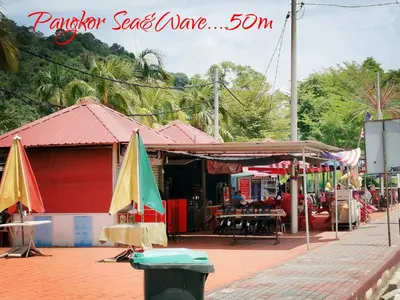 a market with umbrellas in front of a building at Sea & Wave #1 Coral Bay Apartment in Pangkor