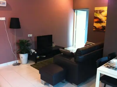 a living room with a couch and a tv at The Osborne Apartments in Ipoh