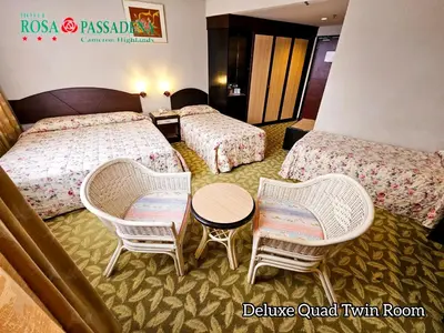 a hotel room with two beds and a table and chairs at Hotel Rosa Passadena in Cameron Highlands