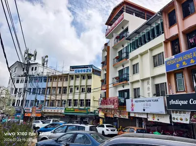 a busy city street with cars parked in front of buildings at Hong Kong Hotel in Brinchang