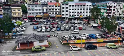 a city with a lot of cars parked in a parking lot at Hong Kong Hotel in Brinchang