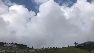 a cloudy sky above a grassy hill with trees at Vin-Cottage Cameron Golden Hills (Next to Night Market) in Cameron Highlands