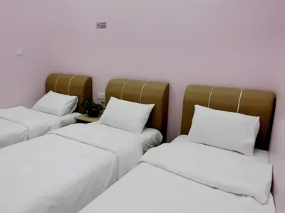 three beds in a room with white sheets and pillows at Taiping Cozy Homestay II in Taiping