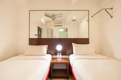 two beds in a room with a mirror between them at Tune Hotel Georgetown Penang in George Town