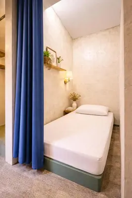 a bed in a room with a blue curtain at Beds In Garden Hostel in Ipoh
